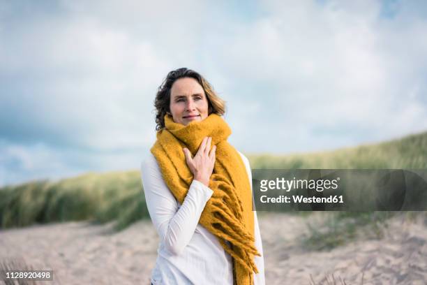 mature woman relaxing in the dunes, enjoying the wind - vrouw 50 jaar stockfoto's en -beelden
