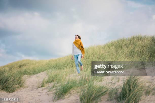 mature woman relaxing in the dunes, enjoying the wind - sand dune stock pictures, royalty-free photos & images