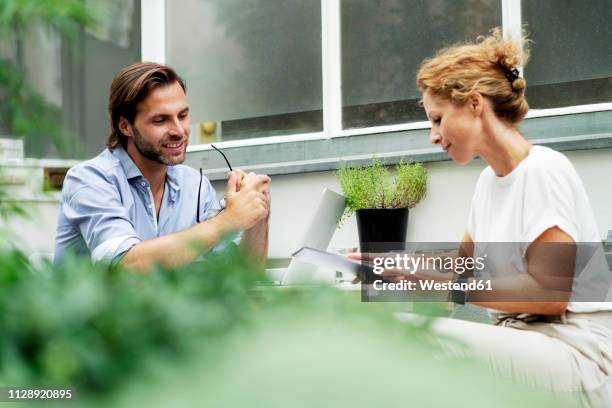 happy couple working from home, sitting in their garden - couple tablet house stock-fotos und bilder