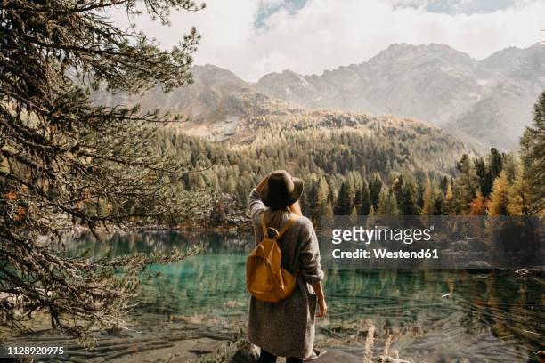 switzerland, engadin, woman on a hiking trip standing at lakeside in mountainscape - switzerland travel stock pictures, royalty-free photos & images