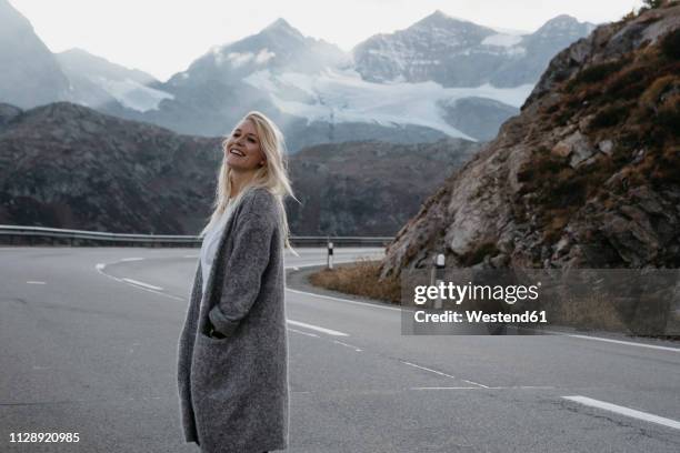 switzerland, engadin, happy young woman standing at the roadside in mountainscape - canton de graubünden photos et images de collection