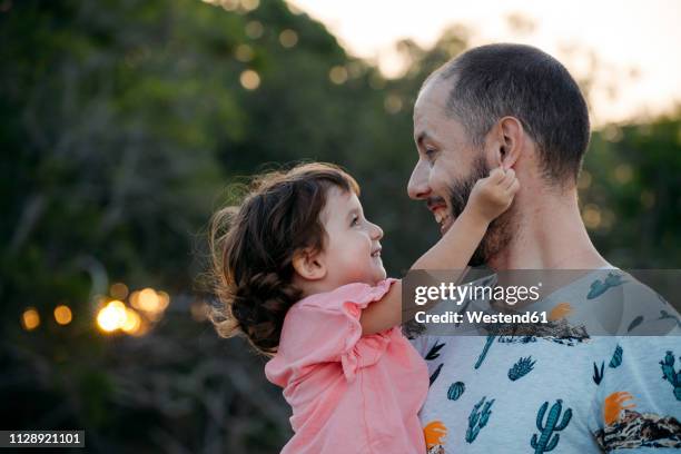 happy father holding his daughter outdoors at sunset - pulling ear stock pictures, royalty-free photos & images