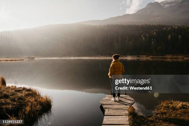 switzerland, engadine, lake staz, woman standing on a jetty at lakeside in morning sun - forest morning light stock pictures, royalty-free photos & images