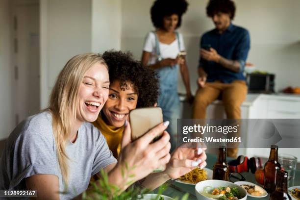 happy girlfriends with cell phone sitting at dining table - woman drinking phone kitchen stockfoto's en -beelden