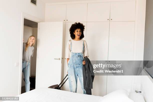 two happy women with baggage arriving in accomodation - om zich heen kijken stockfoto's en -beelden