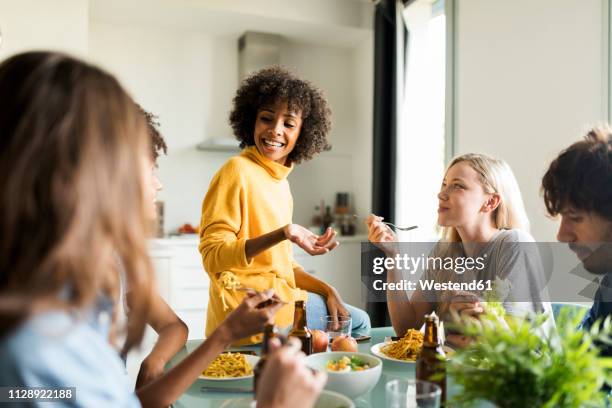 friends sitting at table talking, eating and drinking beer - woman eat noodles imagens e fotografias de stock