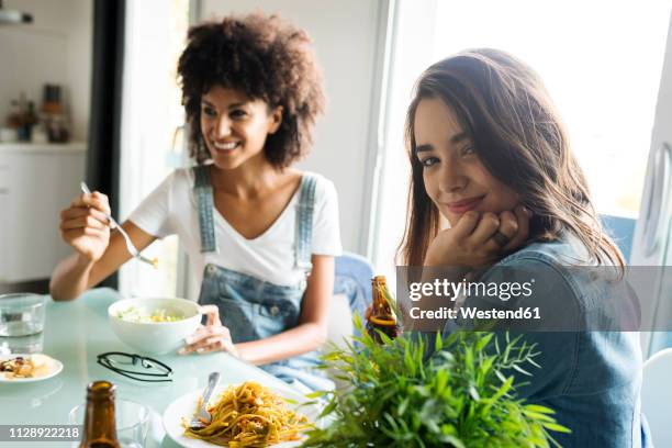 girlfriends sitting at table eating - sitting at table looking at camera stock-fotos und bilder