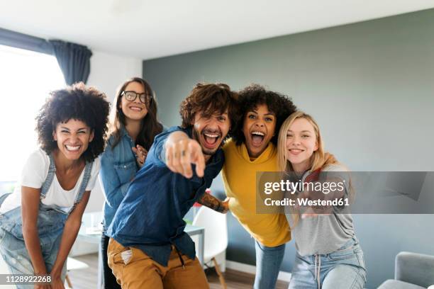 portrait of cheerful friends at home with man and woman pointing finger - five people fotografías e imágenes de stock