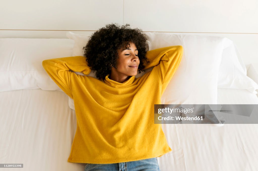 Smiling woman with closed eyes lying on bed