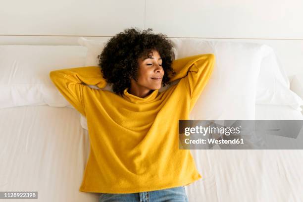 smiling woman with closed eyes lying on bed - women lying imagens e fotografias de stock