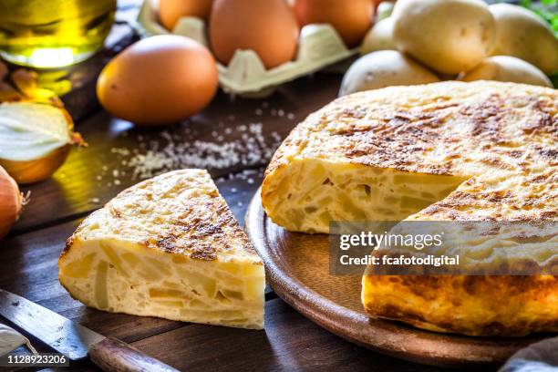 cocina española: tortilla española con ingredientes en mesa de cocina de madera - prepared potato fotografías e imágenes de stock