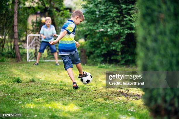 kleine jungs spielen fußball im garten - backyard football stock-fotos und bilder