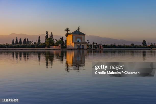 menara garden pavilion at sunrise, marrakech, morocco - with reflection in lake and view to altas mountains. - pavillon de verdure photos et images de collection