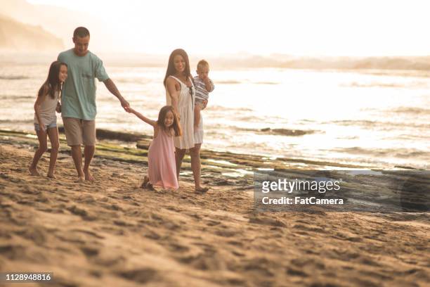 eurasiska mamma och pappa gå längs stranden med sina tre barn - fat guy on beach bildbanksfoton och bilder