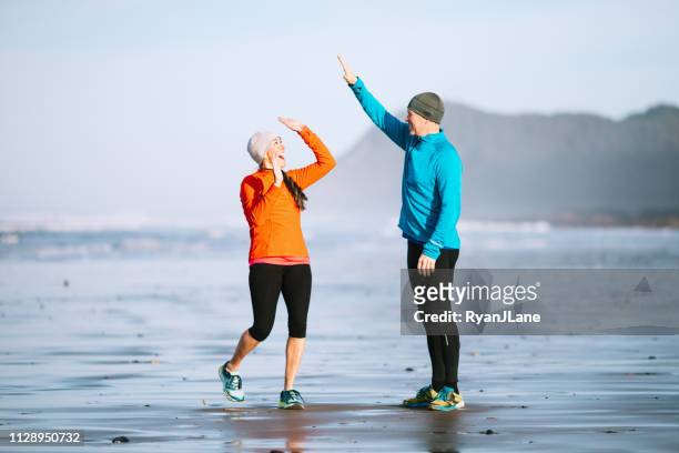 mature adult couple jogging on the beach - mature couple winter outdoors stock pictures, royalty-free photos & images
