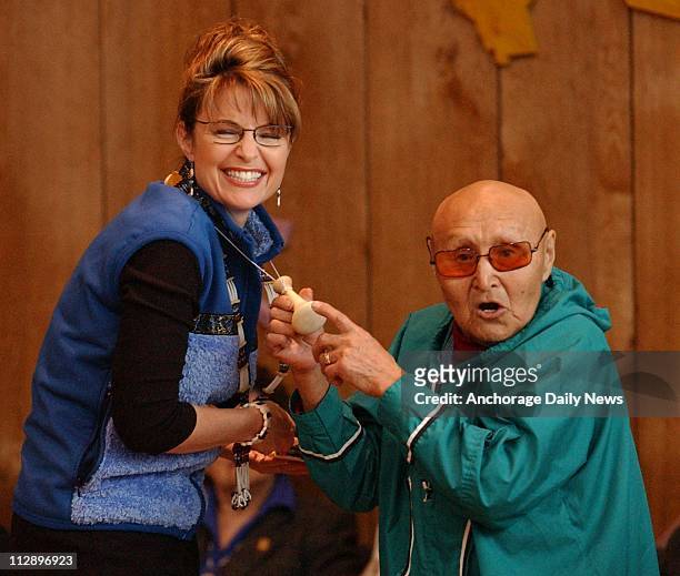 Peter Jacobs of Bethel, right, presents Alaska Gov. Sarah Palin with a tool for pounding fish eggs to make akutaq at a reception honoring the...