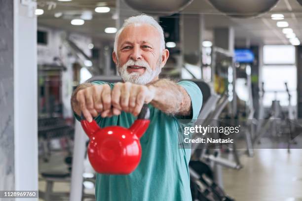 senior hombre en gimnasio usando campanas hervidor - old man fotografías e imágenes de stock