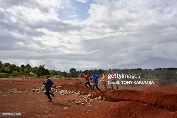 Athletes run a warm up lap along a section of the track that was excavated during construction to upgrade historic Kamariny' stadium, whose progress...