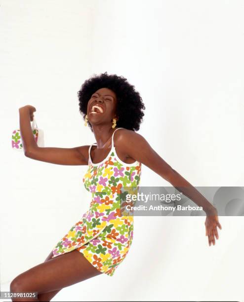 Photo of an unidentified model, dressed in a floral print sundress, as she poses against a white background, New York, 1990s.