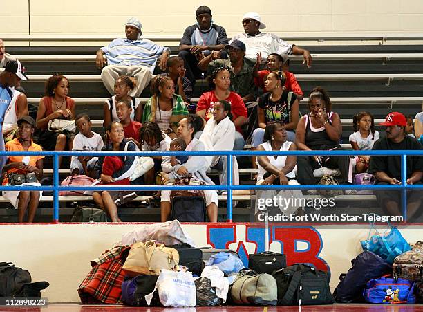 Evacuees wait with their luggage in the gymnasium at West Brook High School in Beaumont, Texas, for bus rides out of town as part of the mandatory...