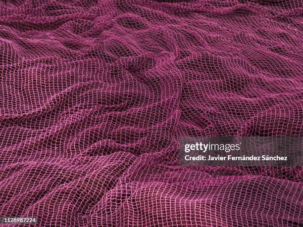 detail of the texture and folds of a fishing net spread on the ground of the fishing port. - fishnet stock pictures, royalty-free photos & images