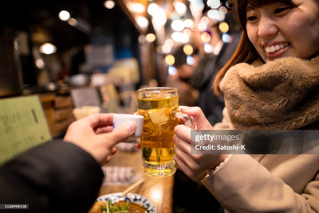 Two people toasting at outdoor standing Izakaya bar