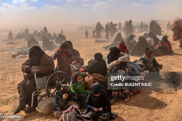 Women and children evacuated from the Islamic State group's embattled holdout of Baghouz sit at a screening area held by the US-backed Kurdish-led...