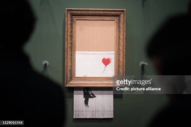 March 2019, Baden-Wuerttemberg, Stuttgart: Visitors stand in front of the shredded Banksy picture "Love is in the Bin" in the Staatsgalerie. The...