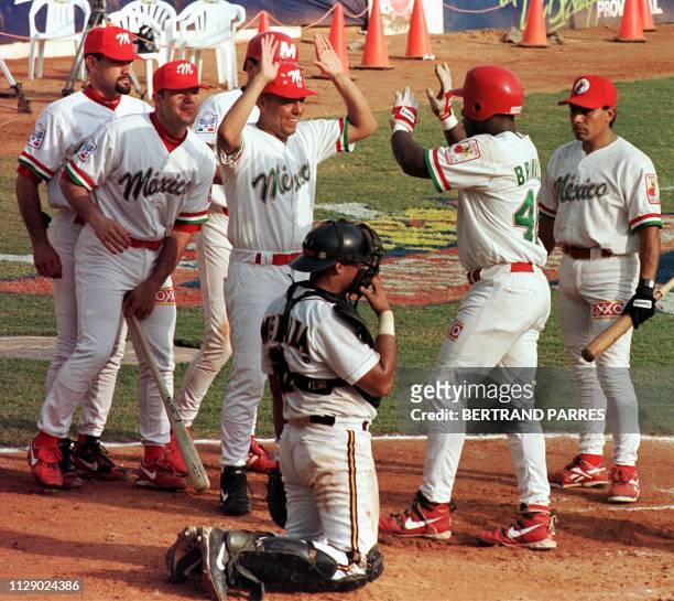 Darrel Brinkley de Mexico es saludado por sus companeros de equipo delante del catcher de Puerto Rico Ben Molina , luego de batear un honron en el...