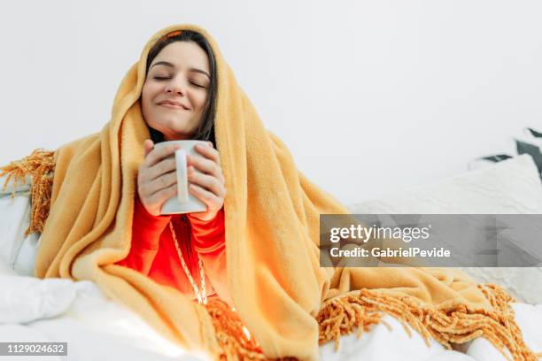 jonge vrouw met koffie onder het dekbed - wrapped in a blanket stockfoto's en -beelden