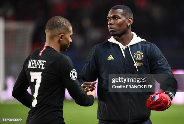 Paris Saint-Germain's French forward Kylian Mbappe shakes hands with Manchester United's French midfielder Paul Pogba at the end of the UEFA...