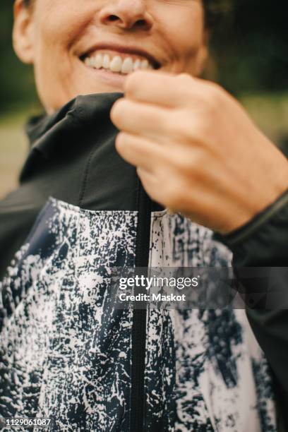 midsection of mature woman zipping jacket in park - zip photos et images de collection