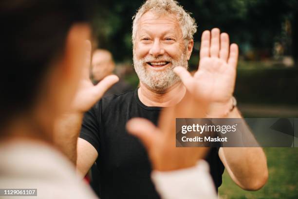 happy sporty man giving high-five to female friend while standing in park - fitness or vitality or sport and women stockfoto's en -beelden