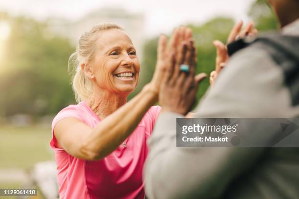 Happy senior woman giving high-five to female friend in park