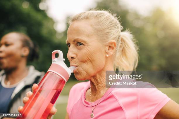 Senior woman drinking water from bottle in park