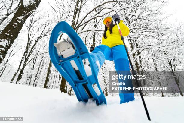 mountain traveler taking a big step with her snowshoe in the deep snow of a frozen forest - snowshoeing stock pictures, royalty-free photos & images