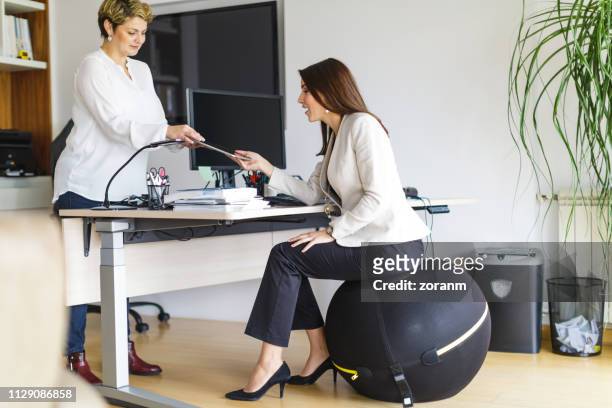 businesswoman sitting on exercise ball at desk - fitness ball stock pictures, royalty-free photos & images