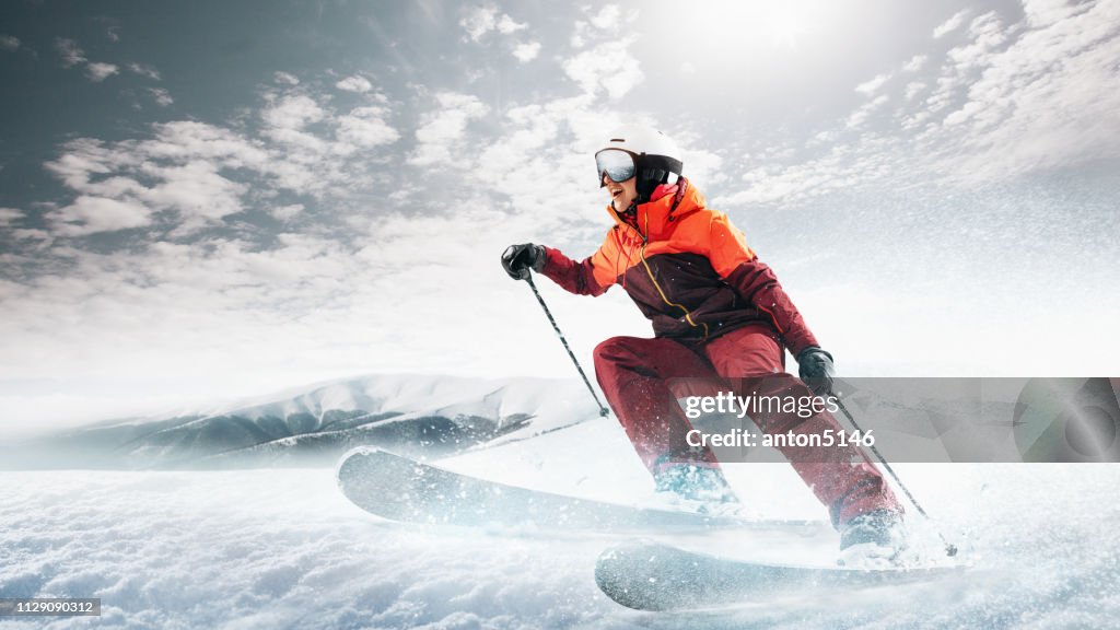 Young woman and winter sport - she is skiing against white alps mountains