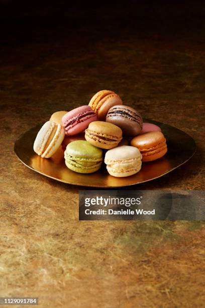 still life with flavoured macaroons on gold plate - macaron stock pictures, royalty-free photos & images