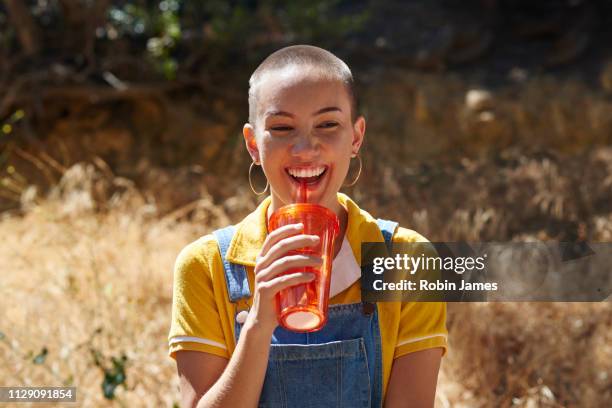 teenage girl with cropped hair drinking from takeaway cup in park, los angeles, california, usa - rietje los stockfoto's en -beelden