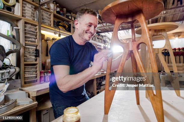 craftsman polishing wooden stool with oil finish - furniture maker foto e immagini stock