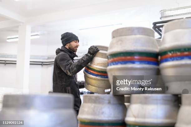 brewer stacking barrels in small brewery - microbrewery stock pictures, royalty-free photos & images