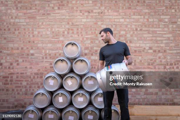 brewer stacking barrels in small brewery - keg stock-fotos und bilder