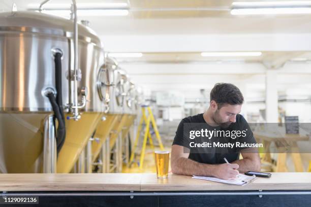 brewer ordering ingredients on phone in small brewery - microbrewery stock pictures, royalty-free photos & images
