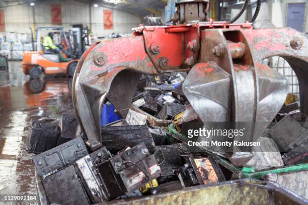 car batteries with crane grab in vehicle battery recycling plant - battery recycling stock pictures, royalty-free photos & images