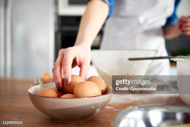 woman taking egg from bowl in kitchen - easter poland stock pictures, royalty-free photos & images