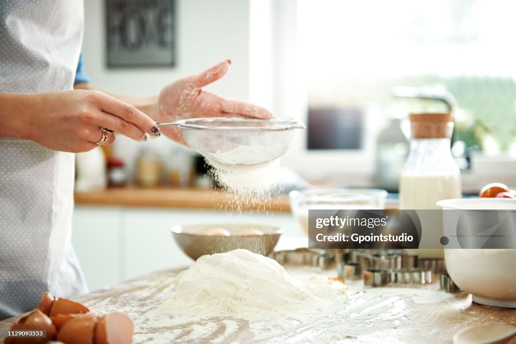 Woman sifting flour in kitchen