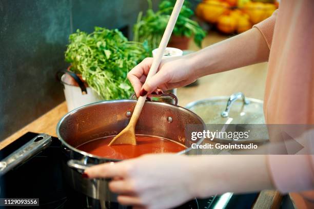 woman cooking tomato soup in kitchen - soep stockfoto's en -beelden