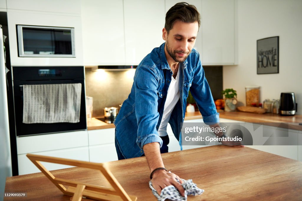 Man wiping table in kitchen