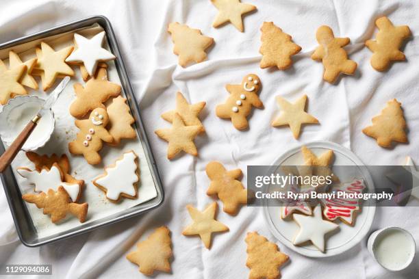 christmas sugar cookies being iced, overhead view - biscuit stock-fotos und bilder